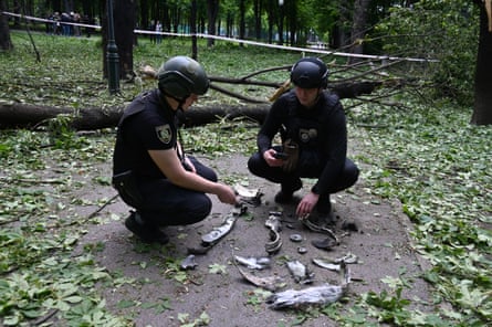 Ukrainian police officers examine fragments of a missile in the central park