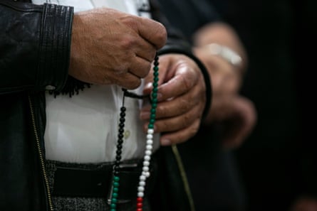 a closeup of hands holding green, white and red prayer beads