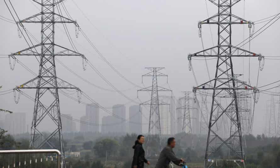 People walk past electricity pylons in Shenyang, China