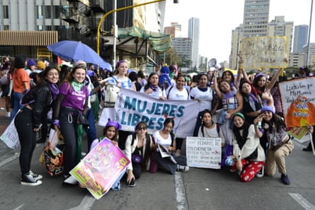 A group of women stand in a street holding signs and placards