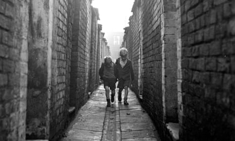 Two boys walking down an alley at the back of terraced houses in Manchester