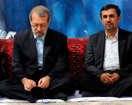 Larijani and Mahmoud Ahmadinejad sitting cross-legged on the floor next to each other