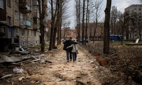 A couple hugs as they walk past a building in Kharkiv heavily damaged by Russian shelling.