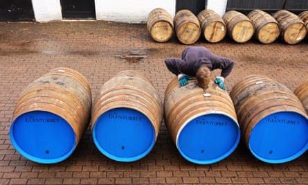 An employee leans over one in a line of barrels waiting to be filled at the Glenturret distillery.