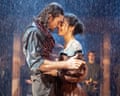 A dark haired man and woman embrace in the rain.