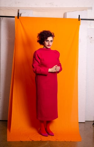 Portrait of a woman in a red dress standing in front of an orange backdrop