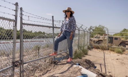 Magali Urbina stands next to a state-built fence and razor wire on her property along the Rio Grande.