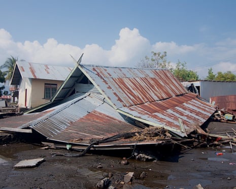 A house collapsed by tsunami floodwaters lies with its rusted metal roof toppled into mud