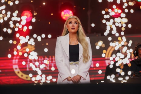 person wearing a white suit and black shirt looks up while on stage person wearing a white suit and black shirt looks up while on stage
