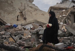 A resident of the village of Aïta el-Chaab holds roses amidst the rubble, January 26, 2025