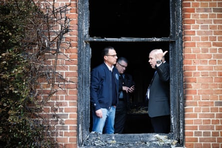 Shapiro stands at a fire-blackened window in conversation with another man