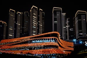 A night-time shot of the Chongqing exhibition hall with skyscrapers lit up behind it