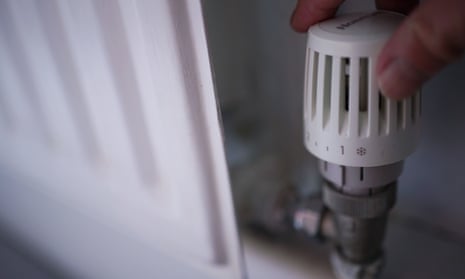 A hand turning the thermostat on a radiator
