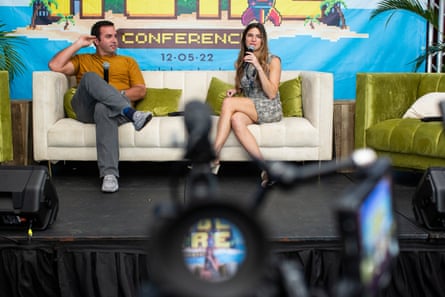 Two speakers sitting on stage on a couch being videotaped at a conference