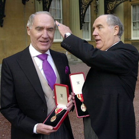 Si kembar Barclay dengan pakaian formal lengkap mempersembahkan medali ke kamera yang baru saja dianugerahi gelar kebangsawanan