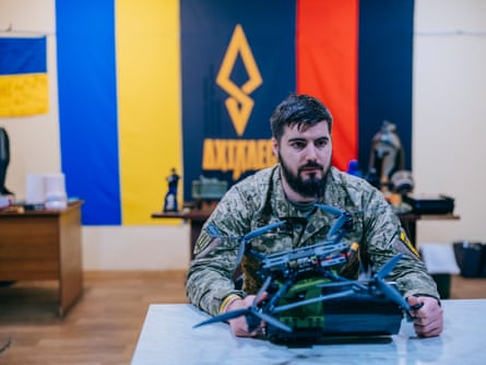 Capt Yuriy Fedorenko, in battle fatigues, sits at a table with a fibre optic drone in front of him
