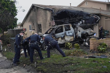police looking at a charred car and home outside