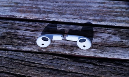 A pair of Apple AirPods 4 resting on a wooden table.