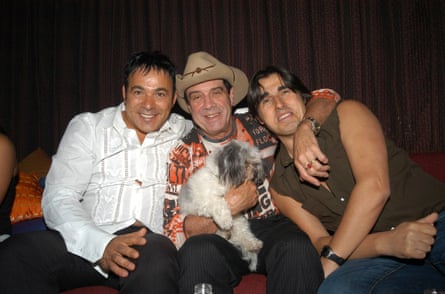 The three men with their arms around each other on a couch in a club