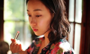a woman looks sad as she applies lipstick