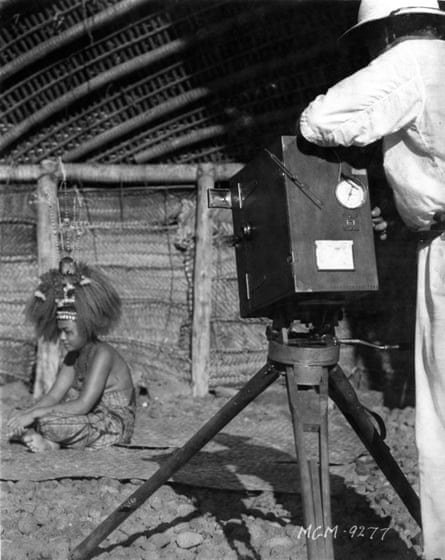 Flaherty shooting Moana on location. figure in colonial whites stands behind a large movie camera facing a woman in traditional dress