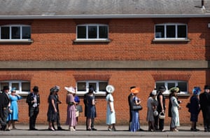 Line of people in elegant outfits next to brick building
