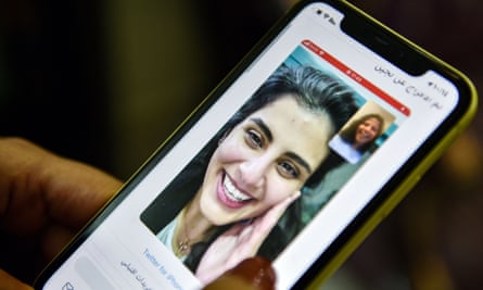 Closeup of phone screen where a woman is viewing a tweet posted by the sister of Saudi activist Loujain al-Hathloul, Lina, showing a screenshot of them having a video call.