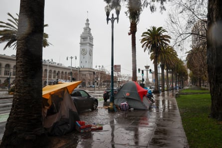 Homeless tents line the sidewalks during a rain storm.