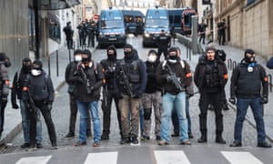 Plain clothes police forces watch proceedings from an avenue off near the Champs Élysées