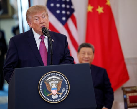 Donald Trump delivering remarks at the White House, with China’s Xi Jinping behind him.