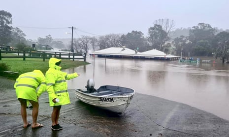 Two people with small boat look out onto flooded road