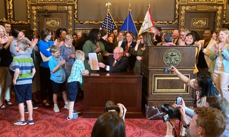 The Minnesota governor, Tim Walz, jokes with kids after signing into law a bill to establish a paid leave program in the state starting in 2026.