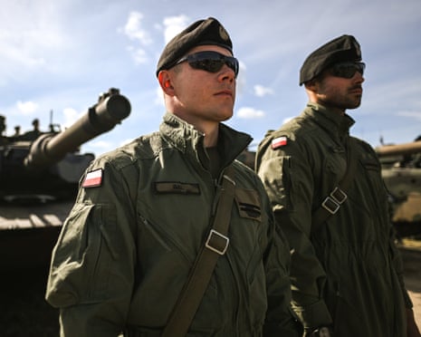 Polish army tank crew members stand in formation before a battle tank