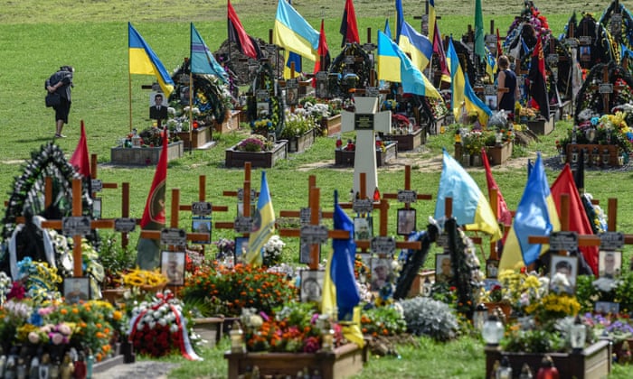 A woman walks past graves during a ceremony for the fallen soldiers of Ukraine at the Lychakiv Cemetery in the western Ukrainian city of Lviv.