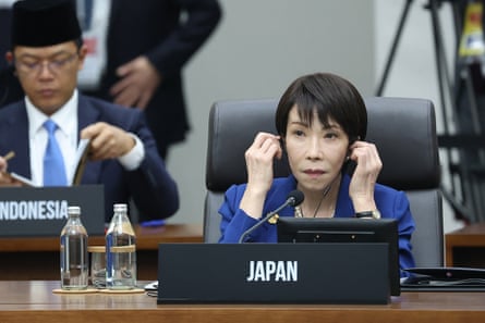 Japan’s prime minister, Sanae Takaichi, sitting at a table putting headphone in her ears