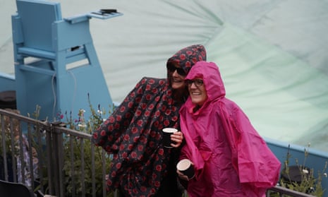 Spectators pose for a picture in front of a covered court as rain stops play during the Queens Club tennis tournament in London, Wednesday, June 19, 2019. (AP Photo/Kirsty Wigglesworth)