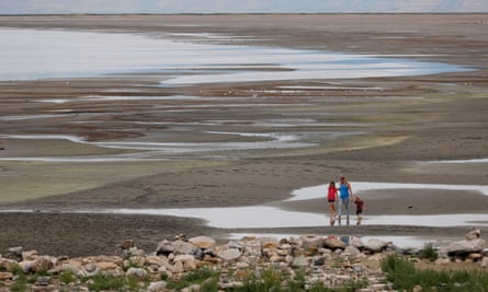 A family walks through puddles of water in a lake bed.