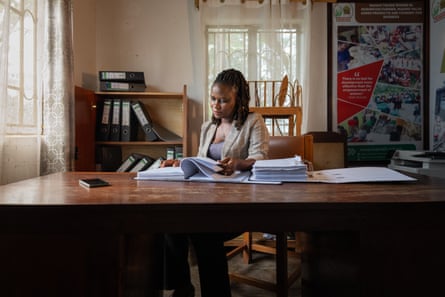 A woman sitting at a desk looking through papers.