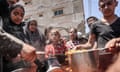 People are handed food at a public kitchen in Deir al-Balah, central Gaza.