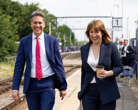 Miliband and Reeves laughing as they walk together beside a railway track outside at a station Miliband and Reeves laughing as they walk together beside a railway track outside at a station
