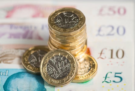 A pile of coins atop sterling banknotes