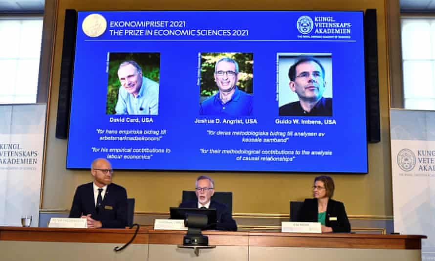 The Sveriges Riksbank prize in economic sciences in memory of Alfred Nobel is announced as photographs of the winners, David Card, Joshua Angrist and Guido Imbens, are presented on a screen