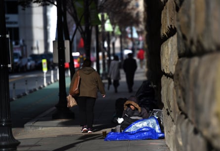 People walk past Robin Riddick as she makes a makeshift space for sleeping along First Street, NE near Union Station in Washington, D.C.