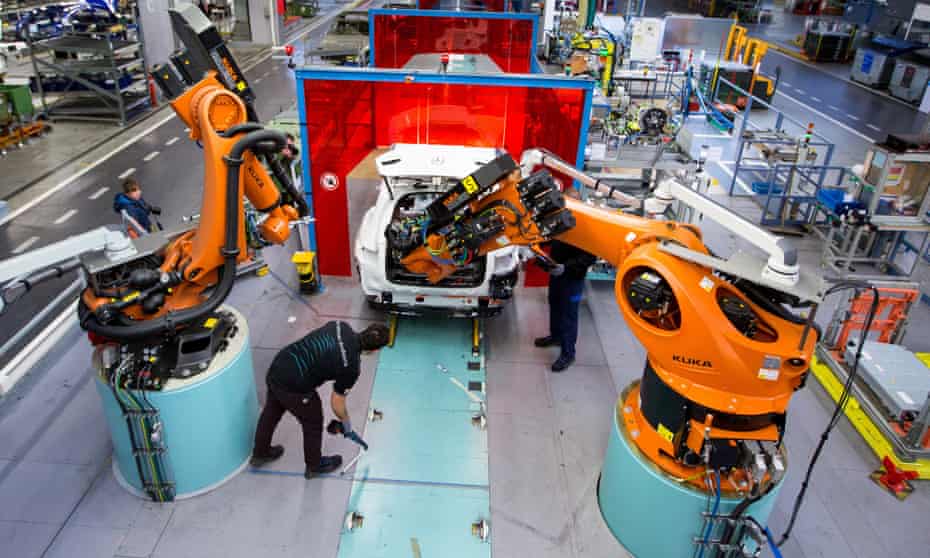 Employees work alongside robotic arms, in a Mercedes-Benz factory in Bremen, Germany