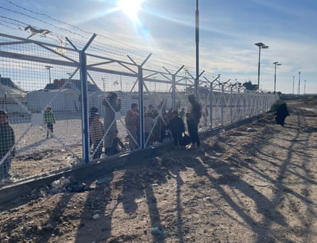 A soldier talks to children through a fence at al-Hawl camp
