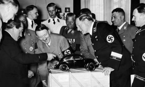 Adolf Hitler admires a model of the Volkswagen car. He is with the designer Ferdinand Porsche and various Nazi officials.