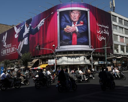 Motorcyclists in Tehran ride past a huge billboard showing a magician and Donald Trump eating