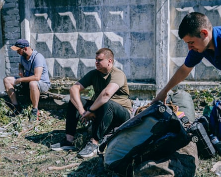 Three Ukrainian men sitting about, one with a bag