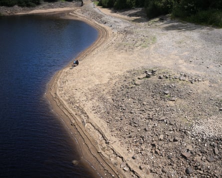 A man fishes from the dried-out bed of a reservoir