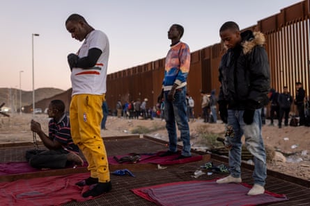 four people pray in front of US-Mexico border wall